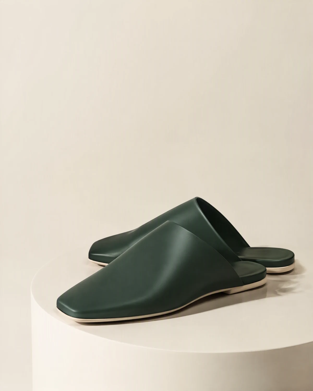 Étude de style d’une paire de mules vertes à large empeigne, posées sur un socle ivoire.