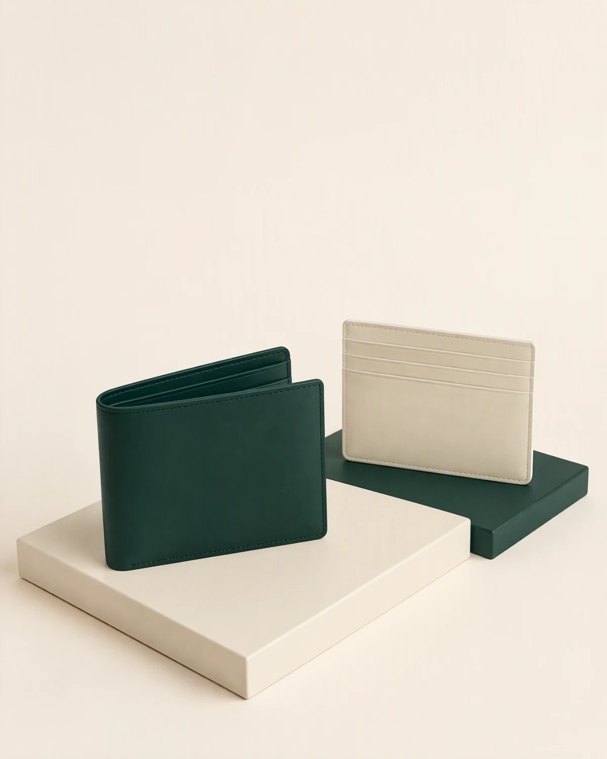 Étude de style d’un portefeuille vert entrouvert et d’un porte-cartes ivoire sur des socles géométriques.